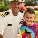 military father with navy uniform on with young son